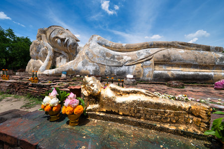 A majestic reclining Buddha statue rests peacefully amidst ancient ruins in Ayutthaya, Thailand. The serene expression of the Buddha and the surrounding natural beauty create a sense of tranquility and spiritual connection.のeditorial素材