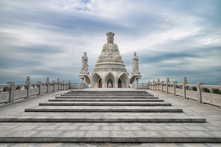 A breathtaking view of a magnificent white marble Buddha statue seated peacefully on a celestial platform. Surrounded by smaller statues and ascending steps, this image exudes tranquility and spirituality. Perfect for meditation, yoga, and religious-themeのeditorial素材