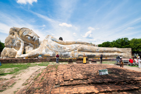 A majestic reclining Buddha statue rests peacefully amidst ancient ruins in Ayutthaya, Thailand. The serene expression of the Buddha and the surrounding natural beauty create a sense of tranquility and spiritual connection.のeditorial素材