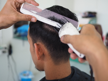 man getting haircut at barber shop. Hairdresser cutting hair of customer at salon.の写真素材