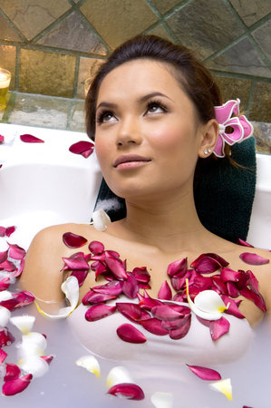 Woman relaxing in bath with plumeria petal