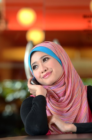 young muslim woman in head scarf using phone in cafeの写真素材