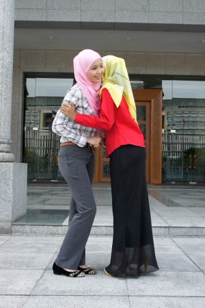 Two young pretty Asian muslim business woman in head scarf shake hand togetheの写真素材