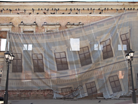 The facade of the house is closed with a protective cloth during the repair. A banner shows the facade of the house. protective cloth as a curtain in the theaterの写真素材