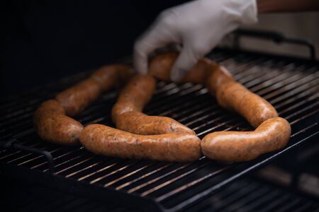 Street food. A man cooking sausages on the grill.の写真素材