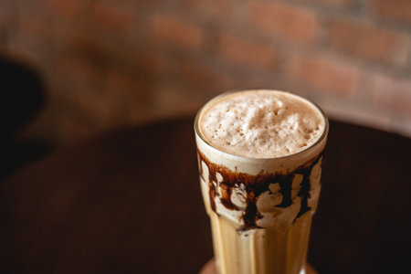 Ice coffee and chocolate on a wood table with brick wall background.