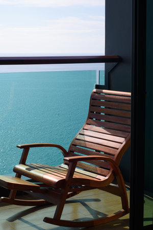 Outdoor wooden chair in front of room and sea view background.