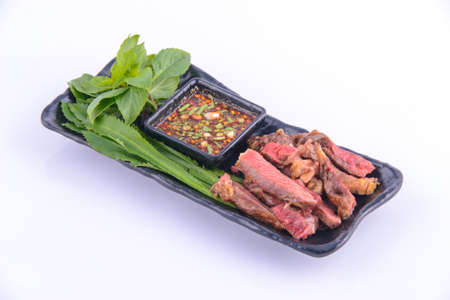 Roasted pork steak on the black plate with thai sauce.の写真素材