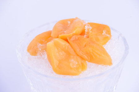 Dried mango on ice in plastic cup on the white background.