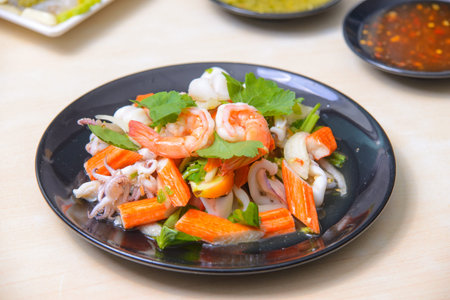 A vibrant and colorful spicy mixed seafood salad featuring fresh shrimp, squid, clab stick and herb on the white background.の写真素材