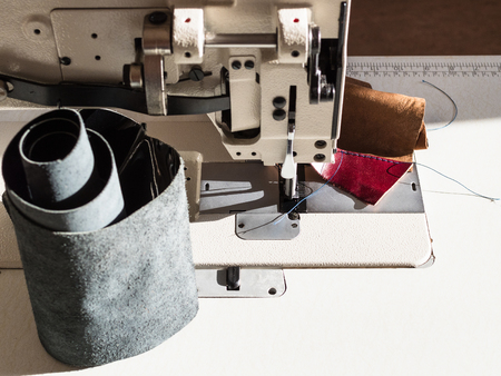 blank leather on table of leather sewing machine in workshop illuminated by sunの写真素材