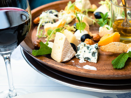 cheese plate appetizer and red wine glass close up in restaurant