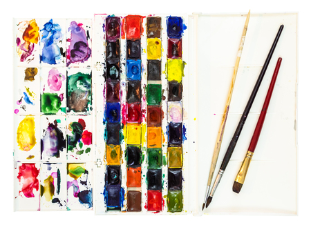 set of used watercolor paints in plastic box with pallet and few paintbrushes in cover isolated on white backgroundの写真素材