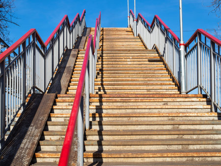 bottom view of high outdoor steel pedestrian stairs in sunny autumn day