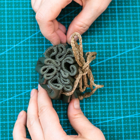 workshop of making the leather bag for jewelry - top view of craftsman hands and folded knotted...