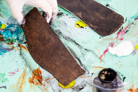 workshop of making the carved leather bag - craftsman stains the carved leather items of handbag