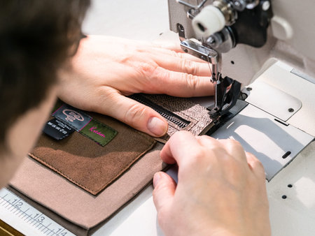 workshop of making the carved leather bag - craftsman sews the inner pocket for leather handbag on...