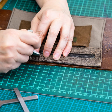 workshop of making the carved leather bag - craftsman punches edge of pocket for handbag by...