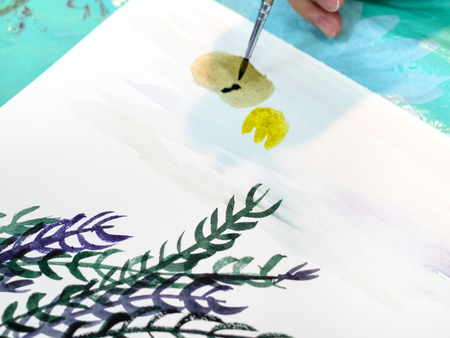 artist paints a picture with a brush with watercolors on a white sheet of paper close upの写真素材