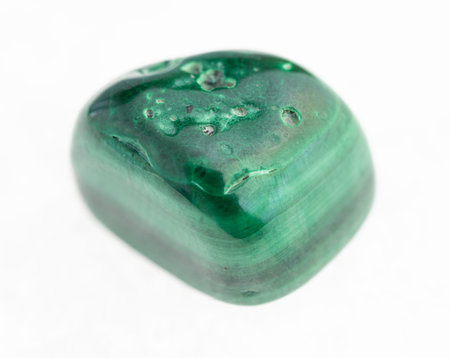macro photography of natural mineral from geological collection - tumbled malachite stone on white...