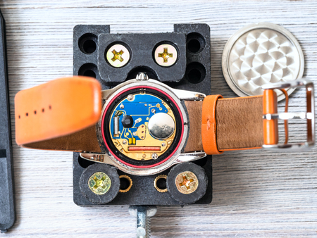 watch repairer workshop - open quartz wristwatch fixed in holder for replacing battery on wooden tableの写真素材