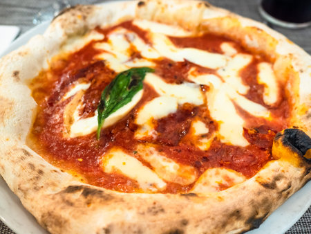 typical italian pizza Diavola with hot spicy salami baked in traditional wood-fired oven in local restaurant in Lombardyの写真素材