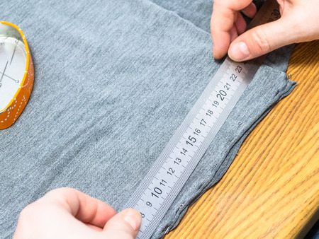 dressmaker marks a gray fabric with ruler on cutting table close upの写真素材