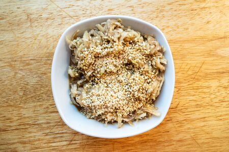 french cuisine - top view of fresh grated kohlrabi salad with sesame seeds and dressing of honey, balsamic vinegar and olive oil in white ceramic bowl on wooden tableの写真素材