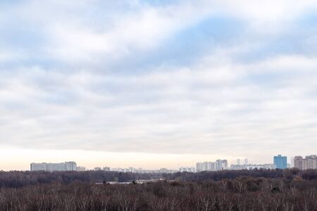cloudy sky over city park and apartment houses on horizon in autumn morningの写真素材