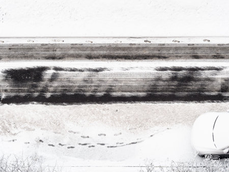 above view of footprints on snow-covered roadside of cleared urban road in winter