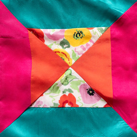 textile background - square fragment of hand-sewn patchwork cloth