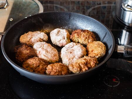 many russian Kotleta (minced beef steaks breaded with flour) in hot pan on ceramic stove at home kitchenの写真素材