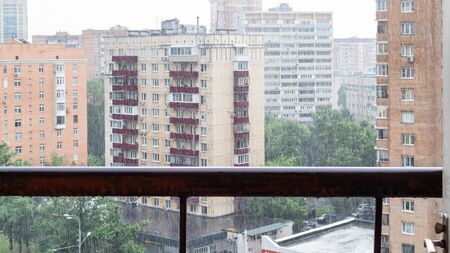 panoramic view of wet balcony railing and residential district in rain in Moscow city in summerの写真素材