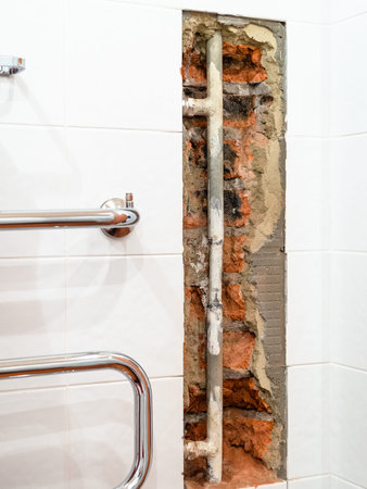 repairing of plumbing riser of heated towel rail at home - old water supply pipe in broken wall