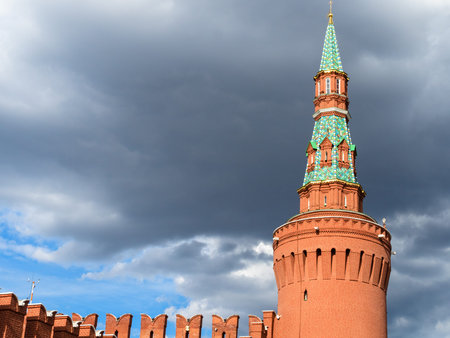 view of Kremlin Wall with Beklemishevskay Tower and gray rainy cloud in blue sky during city...