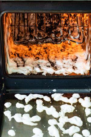 cleaning oven in home kitchen - glass door and chamber of dirty oven covered by reagentの写真素材