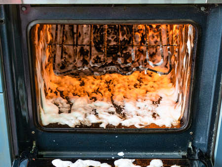 cleaning oven in home kitchen - inner chamber of dirty oven covered by reagentの写真素材