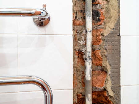 repairing of plumbing riser of heated towel rail at home - old water supply pipe in chiseled niche in wallの写真素材