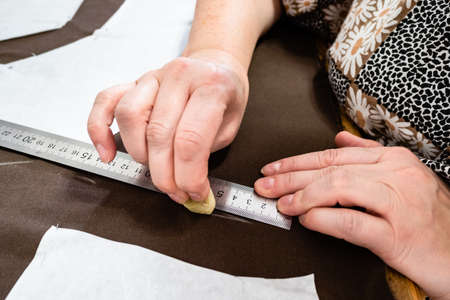 female hand draws pattern of dress on brown fabric by soap close up at homeの写真素材