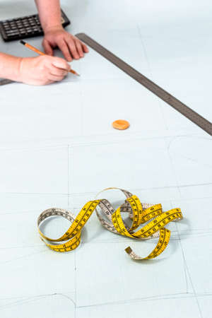 tailor's measure tape on pattern layout of dress drawn on graph paper at home (focus on the tape on foreground)の写真素材