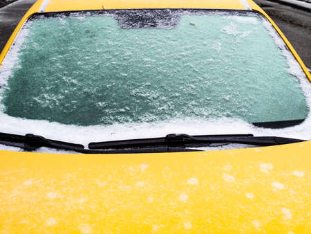 frozen windshield of yellow car close up in city after freezing rain on cold autumn dayの写真素材