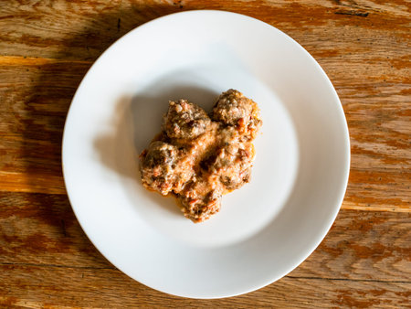top view of portion of meatballs with rice on white plate on old wooden table at home kitchen
