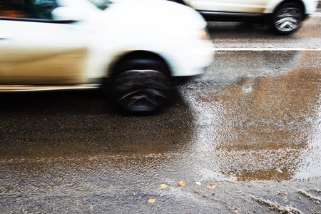 wet city road after melting the first snow and blurred in motion cars on autumn dayの写真素材