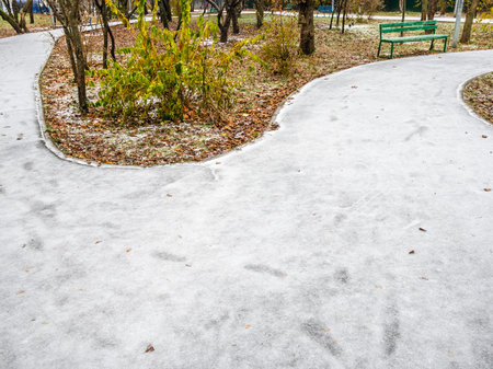ice-covered footpaths and frozen lawn in city park after freezing rain on cold autumn dayの写真素材