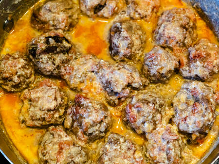 above view of meatballs are stewed in tomato and cream sauce in saucepan at home kitchenの写真素材