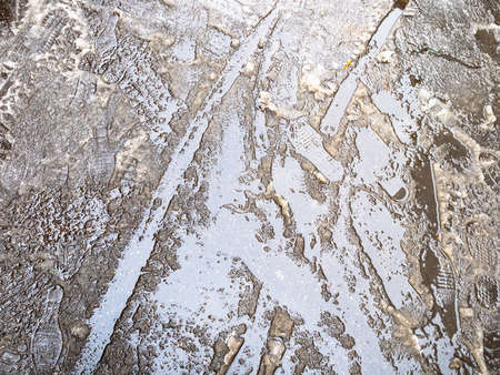 the first melting snow on asphalt surface of city road on autumn dayの写真素材