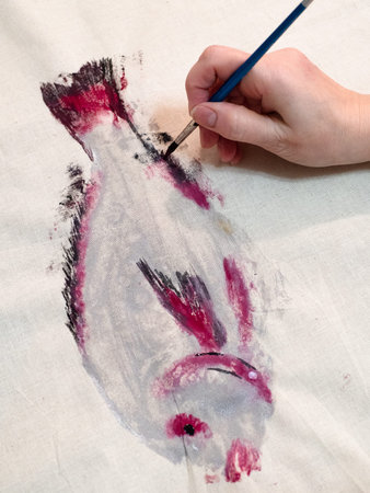 masterclass for Fish Drawing in Technique Monotype - female hand finishes fish print with painbrushの写真素材