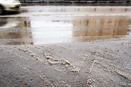 wet surface of highway after melting the first snow and blurred in motion car on autumn dayの写真素材