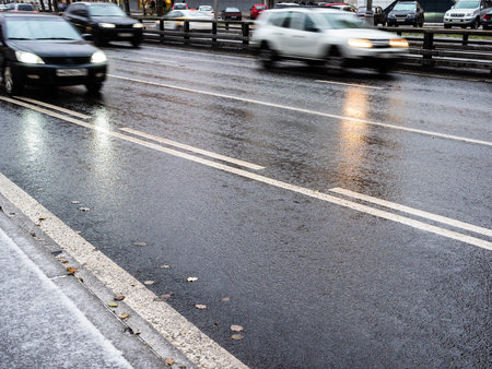 wet surface of city road and blurred in motion cars on autumn evening