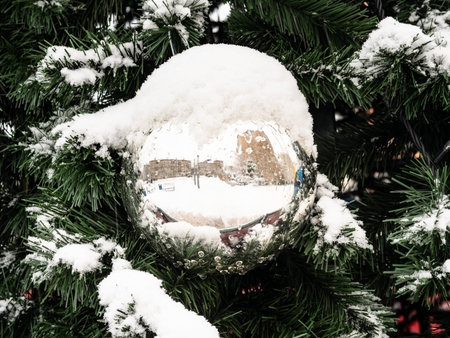 snow-covered mirrored ball on outdoor Christmas tree close up on overcast winter dayの写真素材